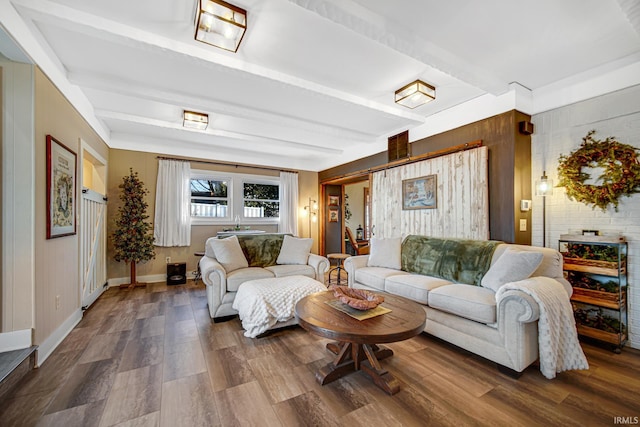 living room featuring beamed ceiling, wood walls, baseboards, and dark wood-style flooring