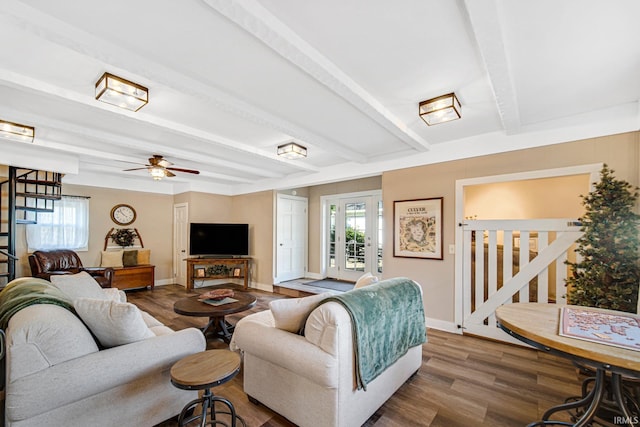 living room featuring beamed ceiling, plenty of natural light, wood finished floors, and baseboards