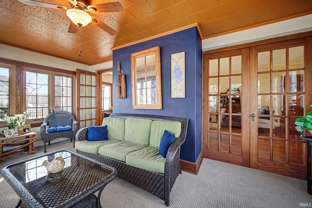 carpeted living room featuring baseboards, an ornate ceiling, ceiling fan, and crown molding