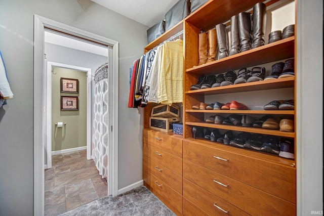 spacious closet featuring stone finish floor