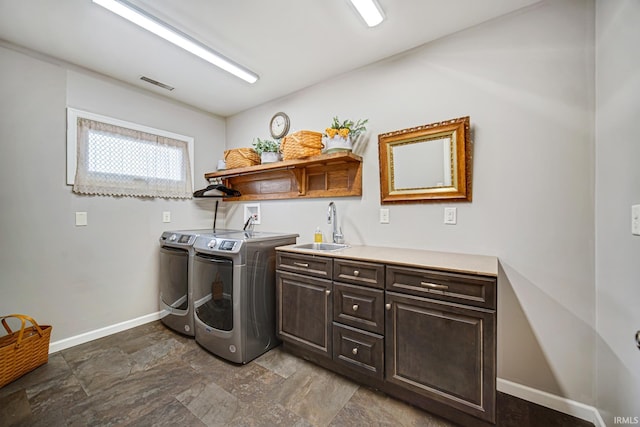 laundry area with visible vents, a sink, washer and dryer, cabinet space, and baseboards