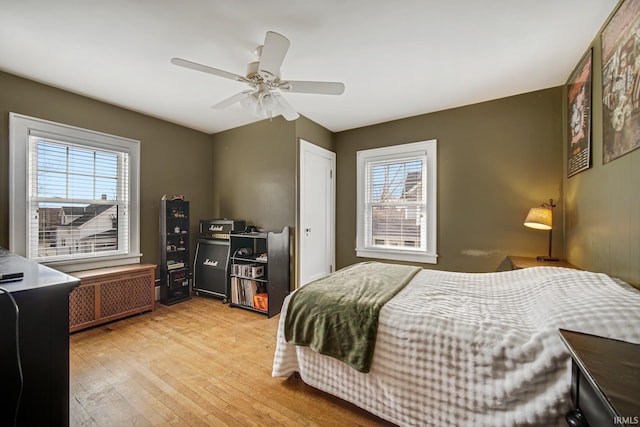 bedroom with light wood finished floors, radiator heating unit, and a ceiling fan