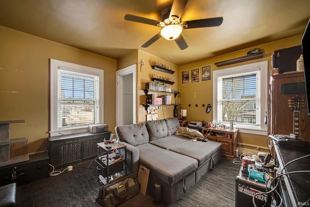 living area with a ceiling fan and dark colored carpet