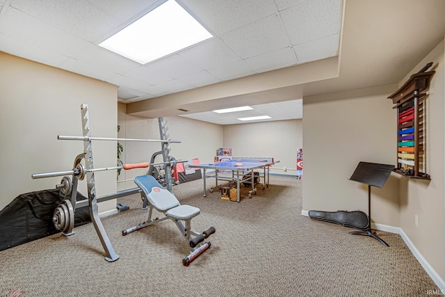 workout room with carpet, a paneled ceiling, and baseboards