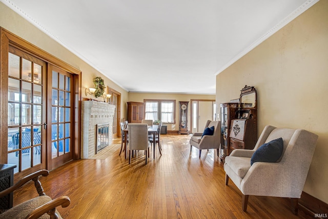 living area featuring wood-type flooring, a brick fireplace, and crown molding