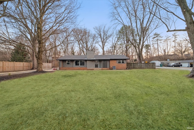 back of house featuring cooling unit, a chimney, a yard, and fence