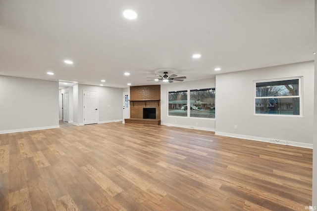 unfurnished living room featuring recessed lighting, a brick fireplace, light wood-type flooring, and a ceiling fan