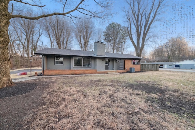 ranch-style house with cooling unit, fence, brick siding, and a chimney