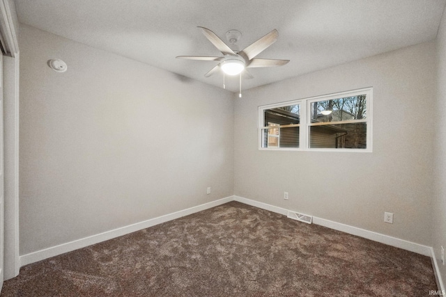 spare room with dark colored carpet, visible vents, baseboards, and ceiling fan