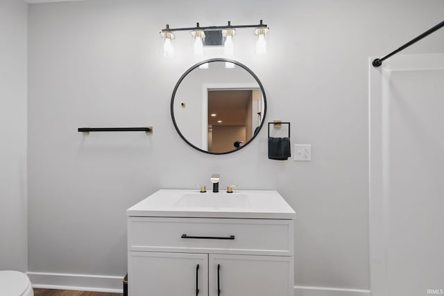 full bathroom with vanity, toilet, baseboards, and walk in shower