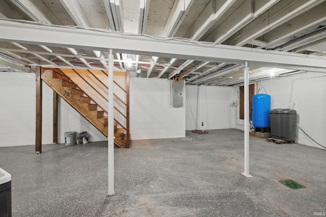 unfinished basement featuring electric panel, stairway, and concrete block wall