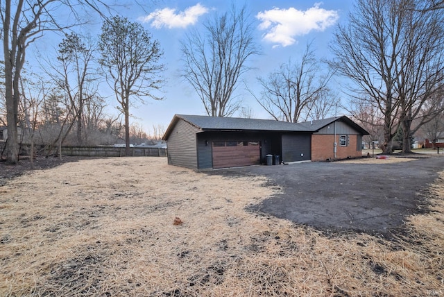 view of outbuilding with driveway, a garage, and fence