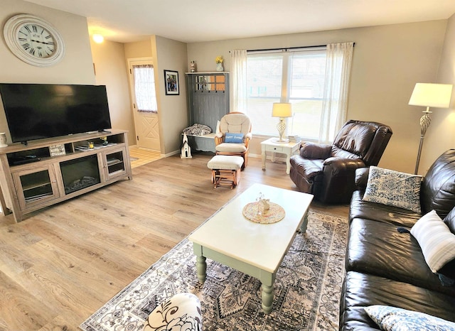 living area featuring light wood-style flooring, baseboards, and a healthy amount of sunlight