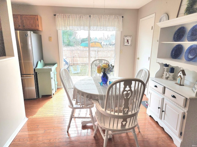 dining space with baseboards and light wood-type flooring