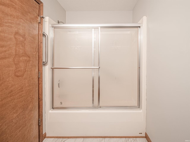 bathroom with combined bath / shower with glass door and baseboards