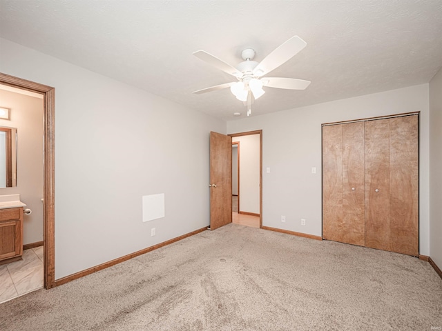 unfurnished bedroom with a closet, light carpet, baseboards, and connected bathroom