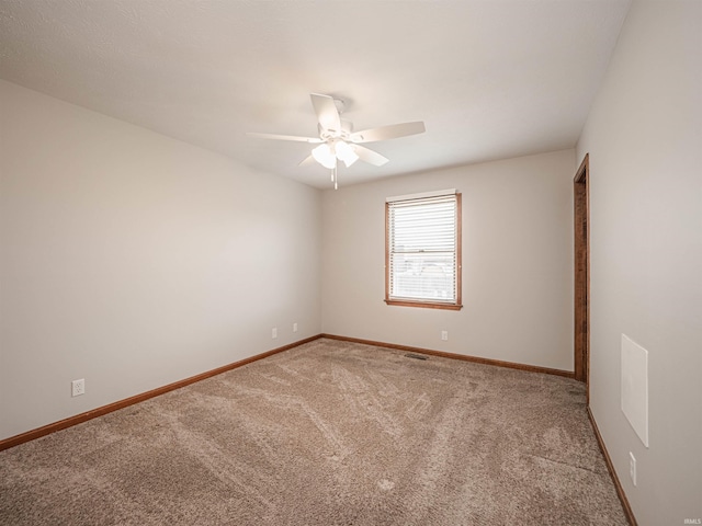 carpeted spare room featuring visible vents, a ceiling fan, and baseboards