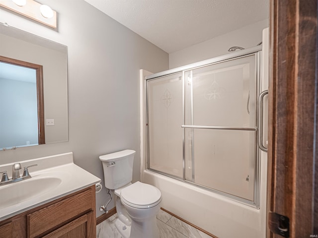 full bathroom featuring baseboards, toilet, vanity, combined bath / shower with glass door, and a textured ceiling