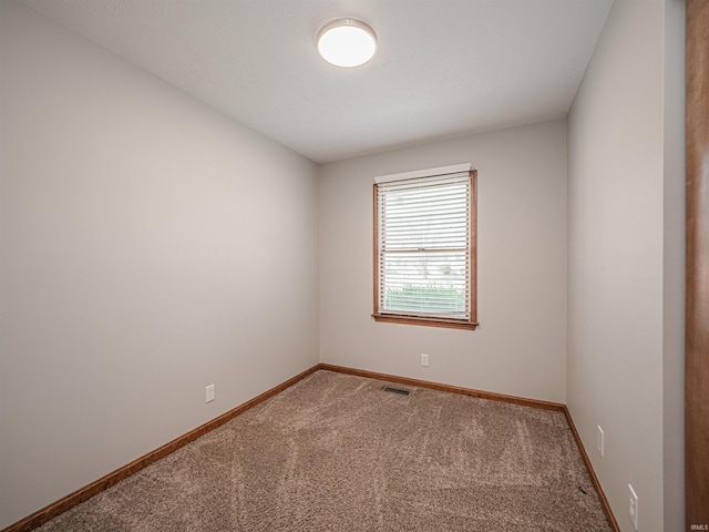 spare room with carpet, visible vents, and baseboards