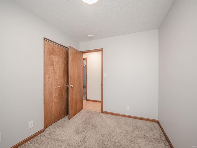 unfurnished bedroom with a closet, baseboards, carpet floors, and a textured ceiling