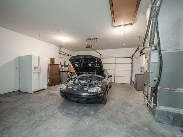 garage with a garage door opener and white fridge with ice dispenser