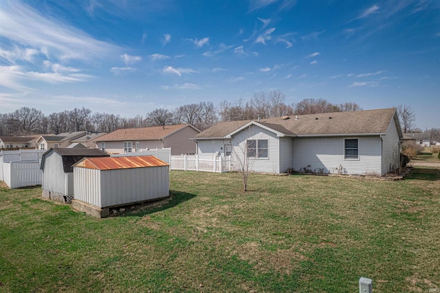 rear view of house featuring an outbuilding, fence, a shed, a yard, and a residential view