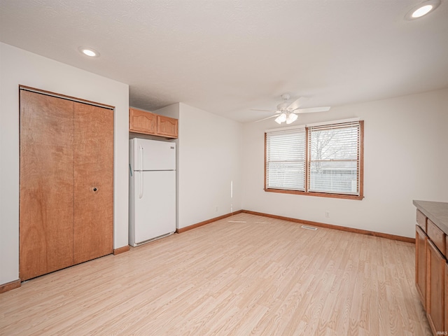 unfurnished bedroom featuring light wood-style flooring, recessed lighting, baseboards, and freestanding refrigerator