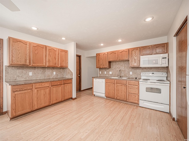 kitchen with backsplash, recessed lighting, light wood-style flooring, white appliances, and a sink