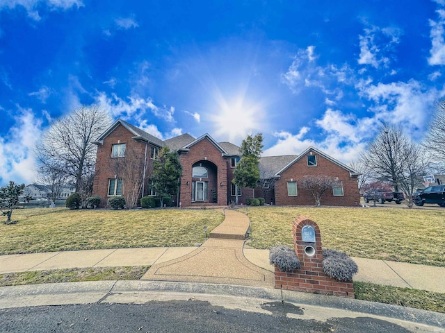 traditional-style house with brick siding, a shingled roof, and a front yard