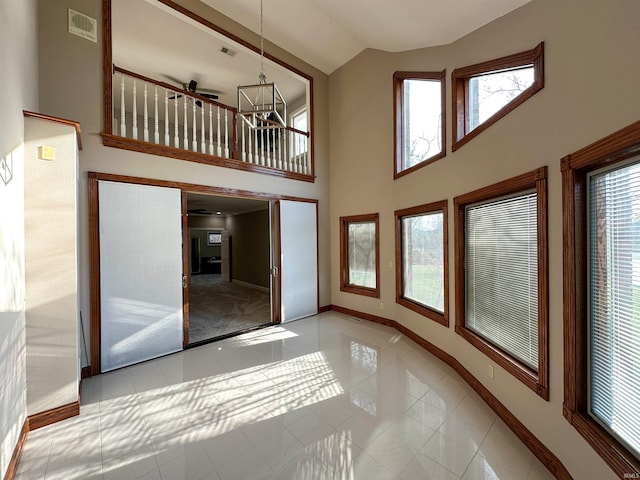 unfurnished living room with visible vents, high vaulted ceiling, tile patterned flooring, baseboards, and ceiling fan