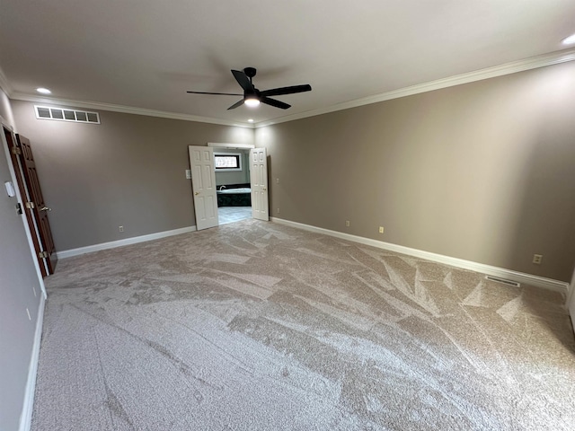 unfurnished room featuring a ceiling fan, visible vents, baseboards, crown molding, and light colored carpet