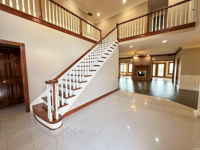 staircase featuring tile patterned flooring, a high ceiling, visible vents, and ornamental molding