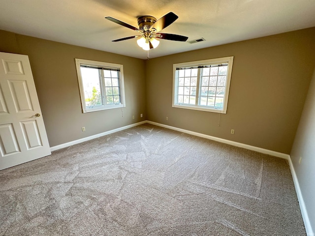 carpeted spare room with visible vents, a ceiling fan, and baseboards