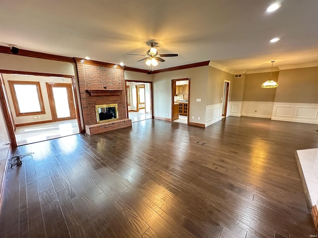 unfurnished living room featuring ornamental molding, a fireplace, a ceiling fan, and dark wood-style flooring