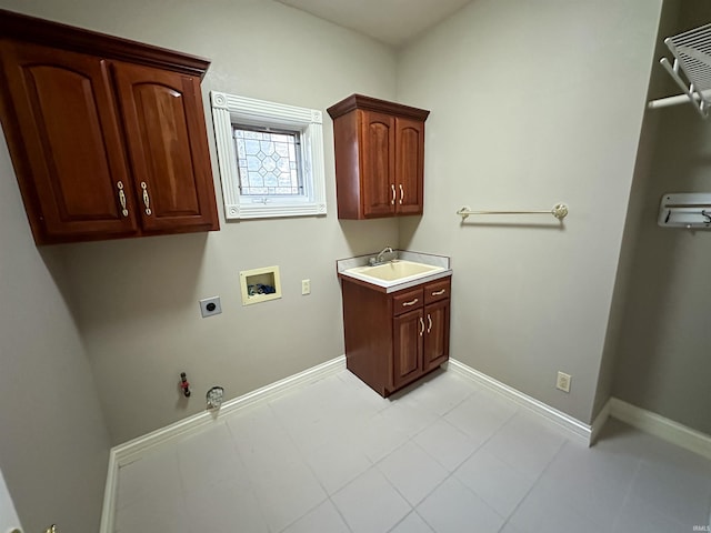 washroom with a sink, hookup for a gas dryer, cabinet space, baseboards, and hookup for an electric dryer