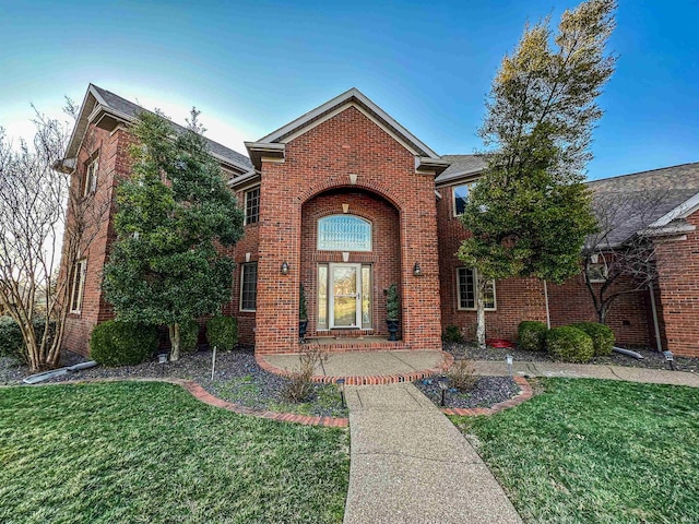 traditional-style house with a front yard and brick siding