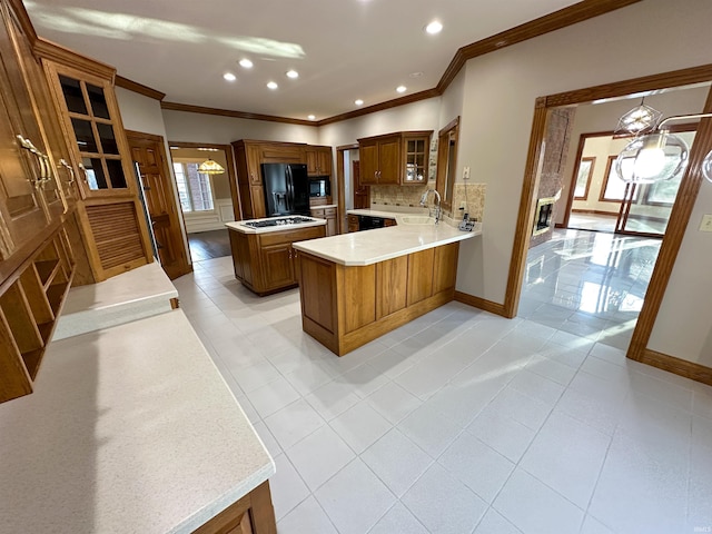 kitchen featuring brown cabinetry, decorative backsplash, black appliances, and a sink