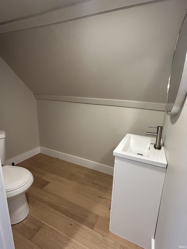 half bathroom with baseboards, toilet, wood finished floors, and vanity