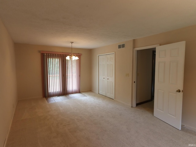 unfurnished room with visible vents, baseboards, an inviting chandelier, a textured ceiling, and light colored carpet