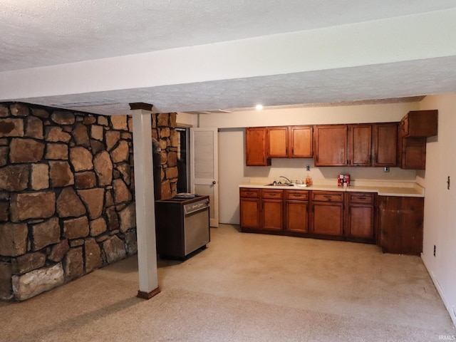 kitchen featuring brown cabinets, a textured ceiling, light countertops, and a sink