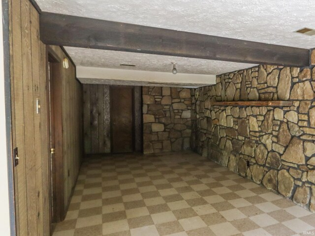 finished basement featuring wooden walls, light floors, and a textured ceiling
