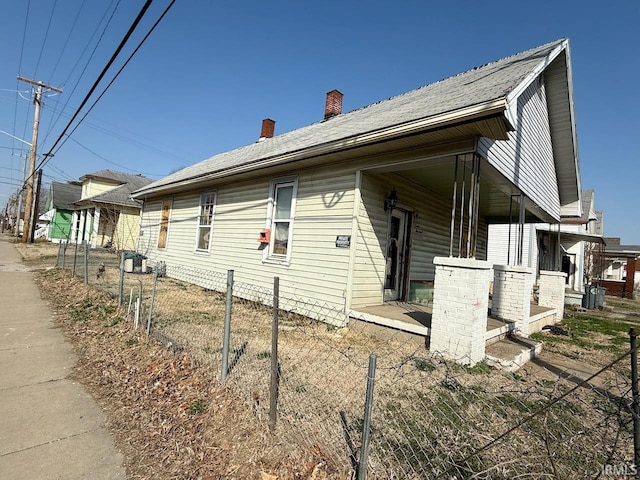 view of home's exterior featuring a porch, fence, and a chimney