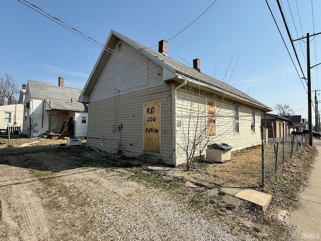 view of side of property with entry steps, fence, and a chimney