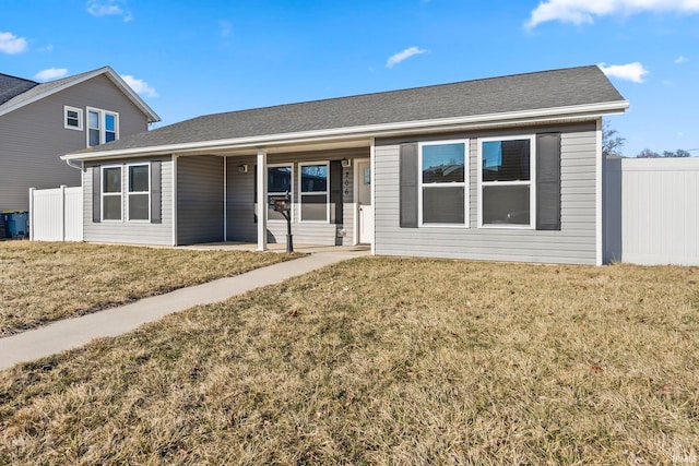 ranch-style house featuring roof with shingles, a front yard, and fence