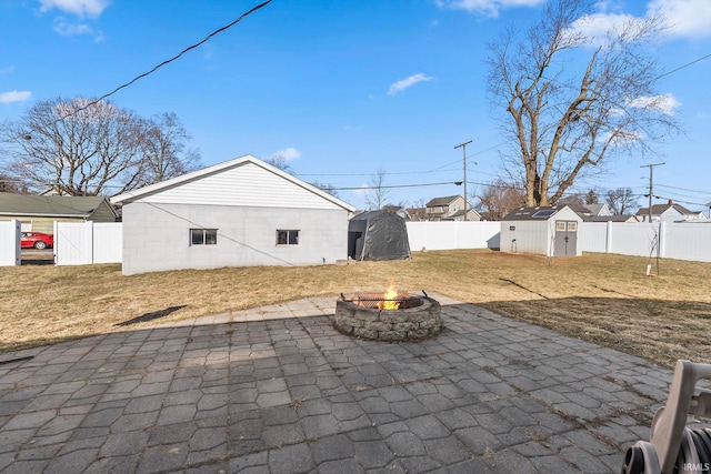 view of patio / terrace featuring a storage shed, a fenced backyard, and a fire pit