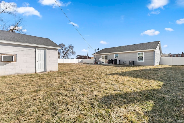 rear view of house featuring a yard, concrete block siding, cooling unit, and fence