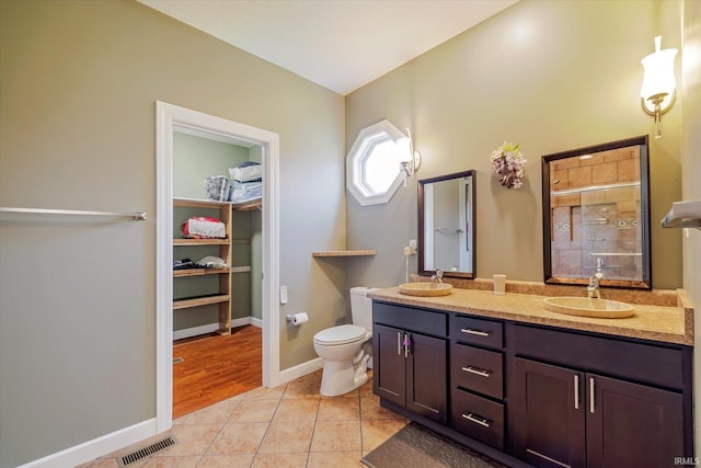 bathroom with visible vents, toilet, a stall shower, a sink, and tile patterned flooring