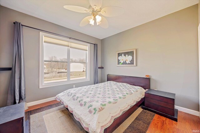 bedroom featuring ceiling fan, baseboards, and wood finished floors