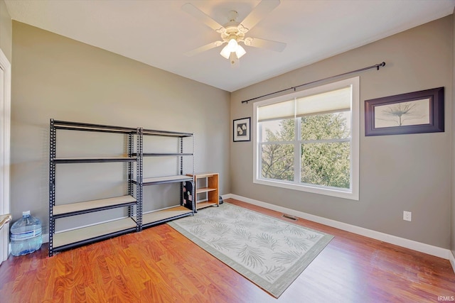 interior space with visible vents, a ceiling fan, baseboards, and wood finished floors