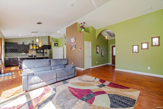 living room featuring lofted ceiling, light wood-style flooring, and arched walkways